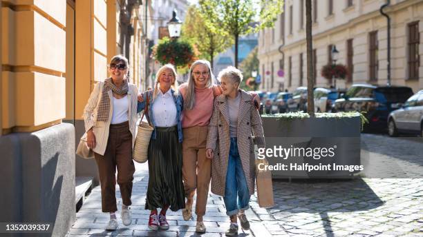 group of happy senior women walking and holding outdoors in town, looking at camera. - nice old town stock pictures, royalty-free photos & images