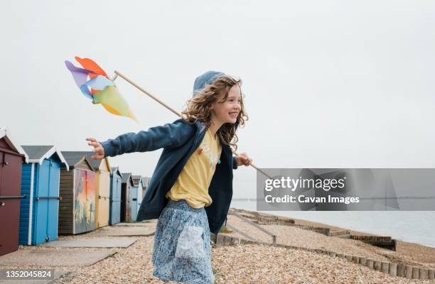 Girl Dancing Happily At The Beach With A Windmill High-Res Stock Photo