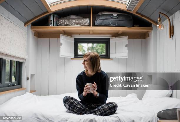 woman enjoying a coffee sat in a shepherd's hut in the cotswolds - shepherd stock pictures, royalty-free photos & images