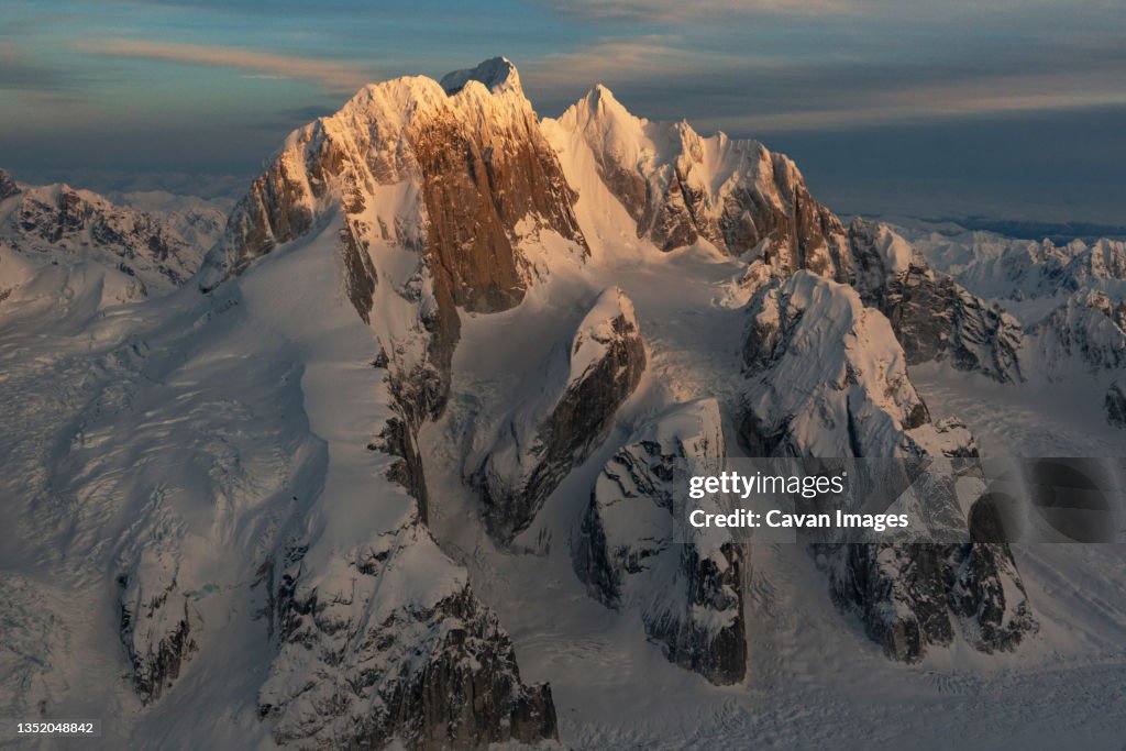 Sunset light shines on snow covered peaks called Moose's Tooth i