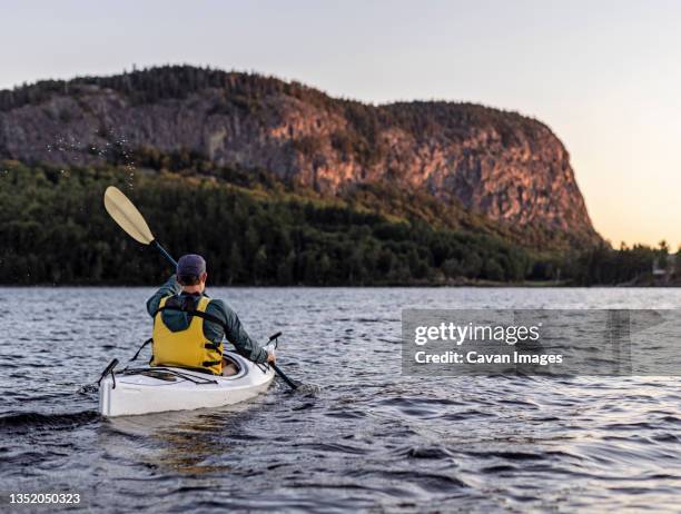 man paddles in kayak across moosehead lake towards mount kineo, maine - summer kayaking stockfoto's en -beelden