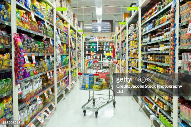 shopping cart in grocery store aisle - abandoned cart stock pictures, royalty-free photos & images