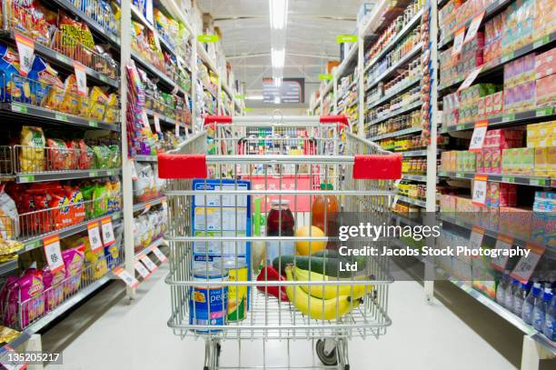 shopping cart in grocery store aisle - shopping trolleys stock pictures, royalty-free photos & images