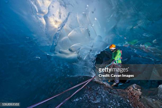 woman exploring icecave on svinafellsjokull glacier - potholing stock pictures, royalty-free photos & images