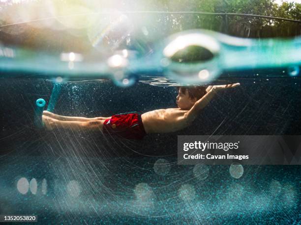 8 years old boy relaxing in a swimming pool - underwater photography through the years stockfoto's en -beelden