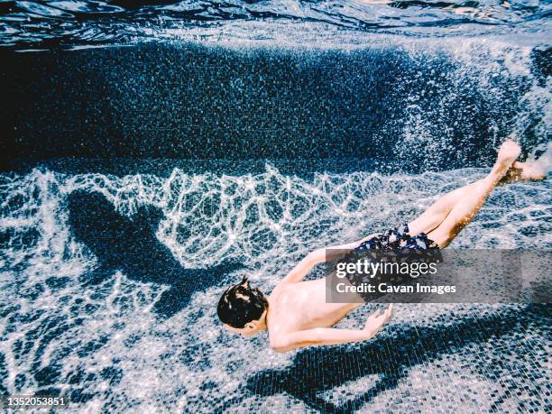 8 years old boy swimming with the shadow of a dolphin in a pool - 8 years stock-fotos und bilder