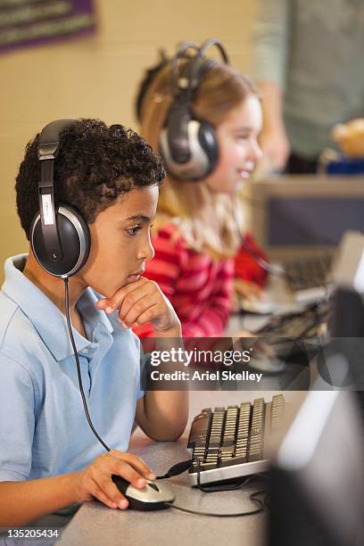 alunos ouvindo para auscultadores em computadores em sala de aula - boy headphones imagens e fotografias de stock