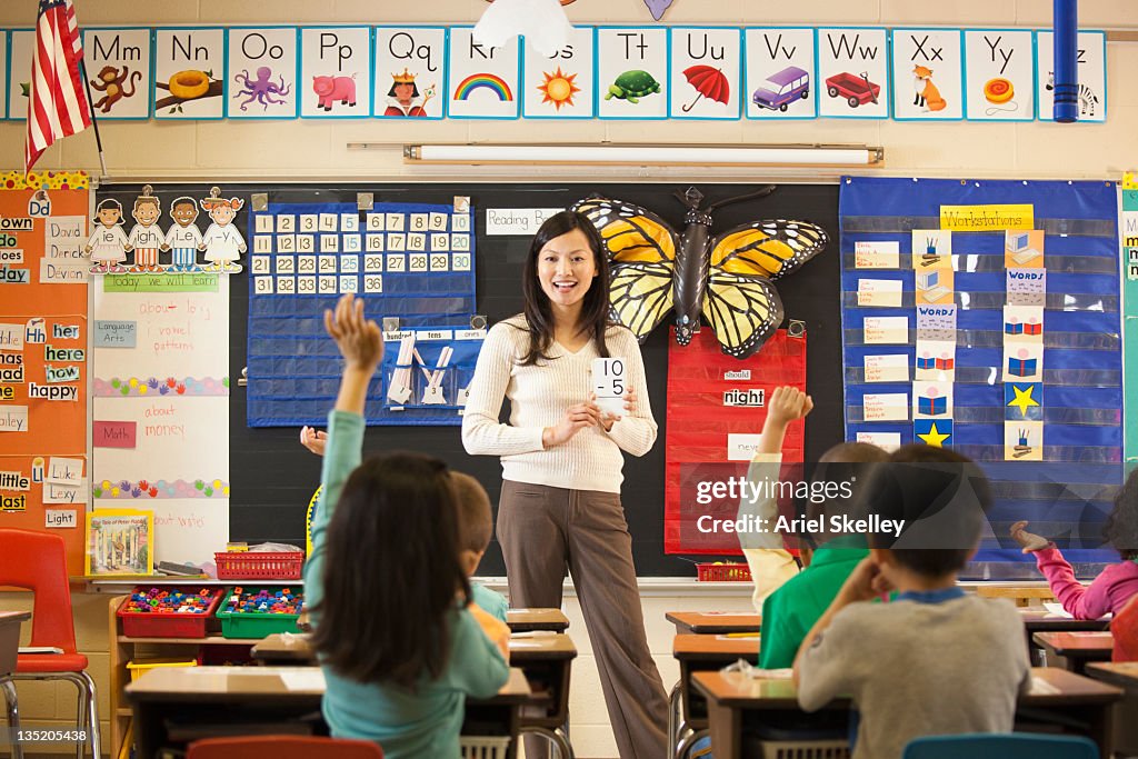 Asian teacher teaching math to students in classroom