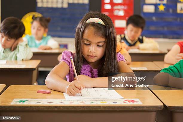 mixed race student studying at desk in classroom - learn arabic stock pictures, royalty-free photos & images