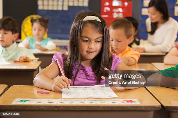 mixed race student studying at desk in classroom - arab student kids stock pictures, royalty-free photos & images