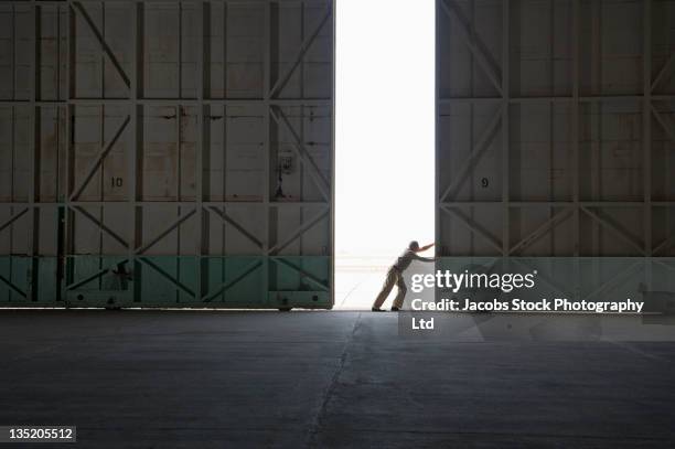 caucasian worker opening large warehouse doors - hanger bildbanksfoton och bilder