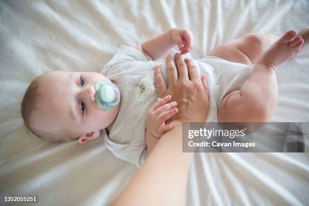 boy lying on bed sucking a pacifier - cólica - fotografias e filmes do acervo