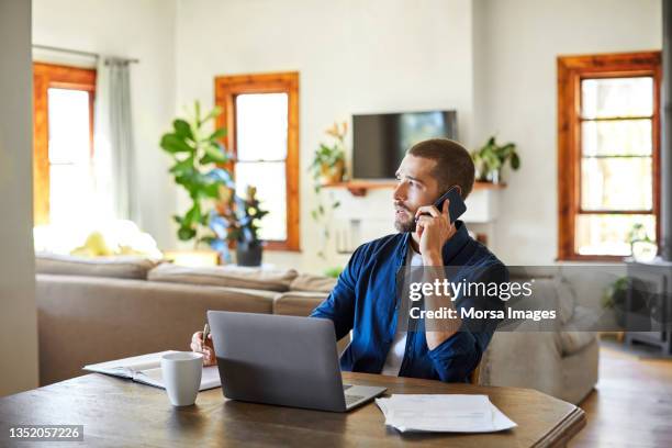 man talking on phone while working from home - 20s talking serious bildbanksfoton och bilder
