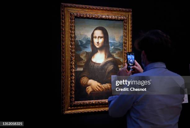 Visitor wearing a protective face mask takes a picture of a Mona Lisa version by Italian artist Leonardo da Vinci at the Artcurial auction house on...