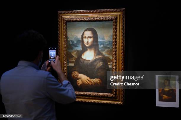 Visitor wearing a protective face mask takes a picture of a Mona Lisa version by Italian artist Leonardo da Vinci at the Artcurial auction house on...