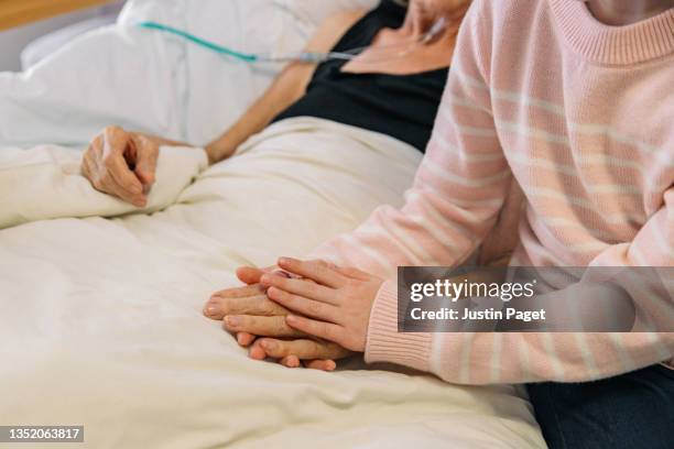 young girl holds the hand of her ill grandmother - stroke stockfoto's en -beelden