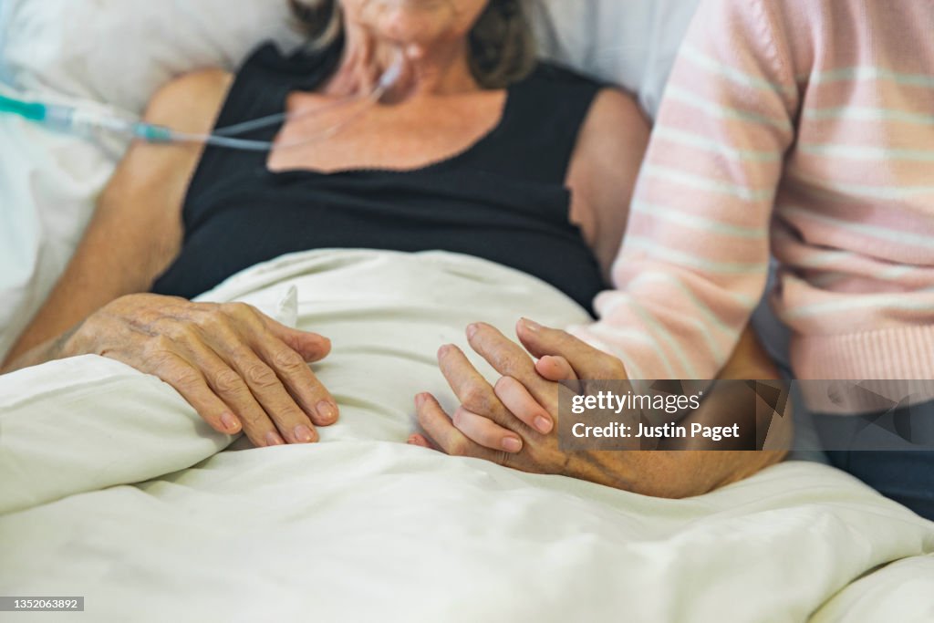Young girl holds the hand of her ill grandmother