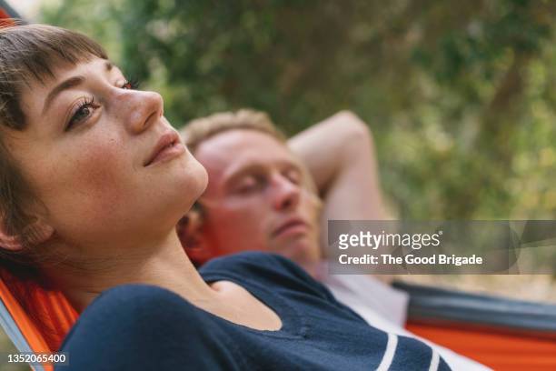 close up of young woman relaxing in hammock with man - a young couple stock-fotos und bilder