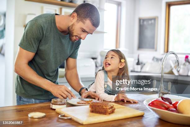 uomo in piedi con la figlia mentre fa il panino - colazione bambini foto e immagini stock