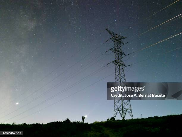 electrician repairing a high voltage electrical tower at night in the mountains. - telefoondraad stockfoto's en -beelden
