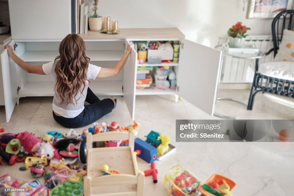 A woman is organizing her daughter's toys in the living room