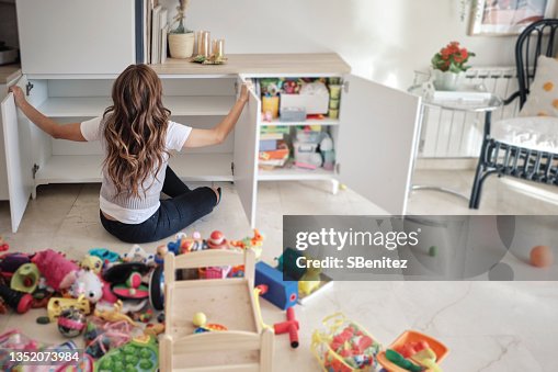 A woman is organizing her daughter's toys in the living room A woman is organizing her daughter's toys in the living room