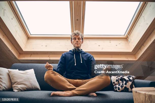 young man meditates below skylights on sofa - navy blue living room stock pictures, royalty-free photos & images