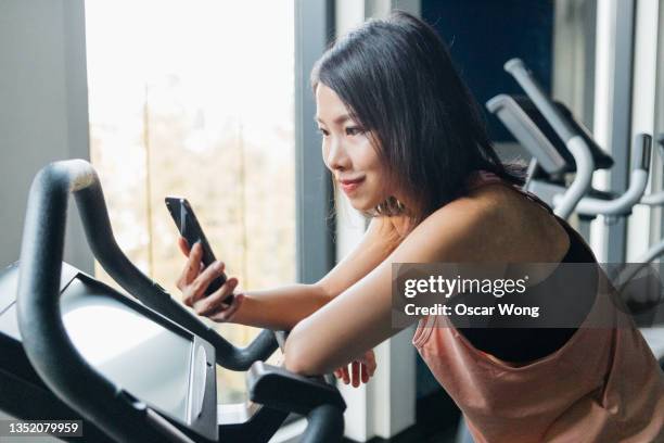 young woman using smart phone while exercising on treadmill - トレッドミル　女性 ストックフォトと画像