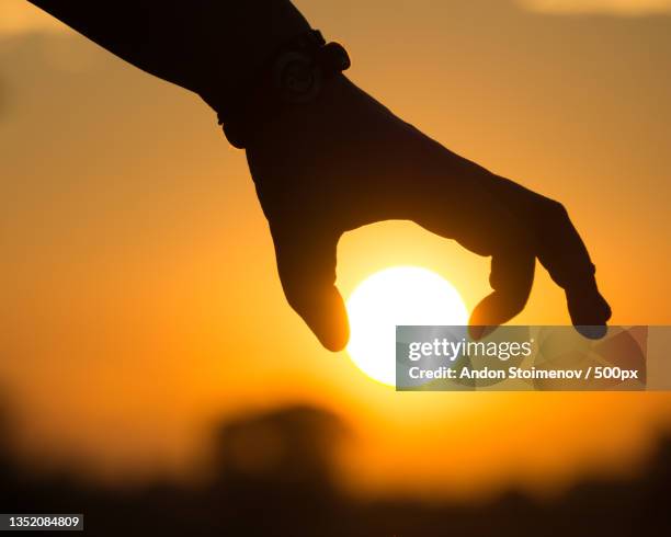 cropped silhouette of hand holding sun against sky during sunset - hands sun stock-fotos und bilder