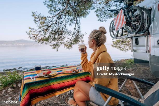 woman enjoys breakfast near her van, beach view - rv beach stock pictures, royalty-free photos & images