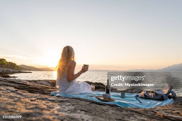 young woman enjoys a red wine by the sea at sunset - croatia food stock pictures, royalty-free photos & images