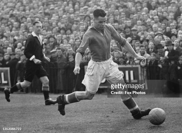 Referee RJ Leafe looks on as Billy Liddell from Scotland and Outside Left for Liverpool Football Club running with the football prepares to pass...
