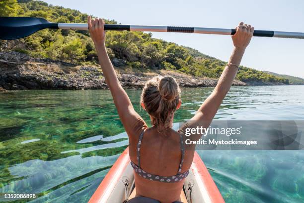 rückansicht der frau auf dem kanu, arme hoch - kayaker woman stock-fotos und bilder