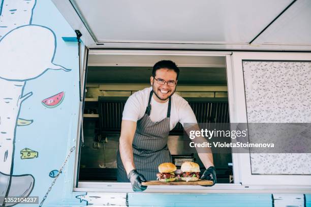 food truck owner serving burgers. - foodtruck stockfoto's en -beelden
