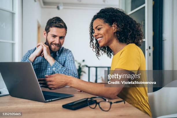 des partenaires commerciaux confiants travaillant sur un ordinateur portable au bureau. - couple souriant photos et images de collection
