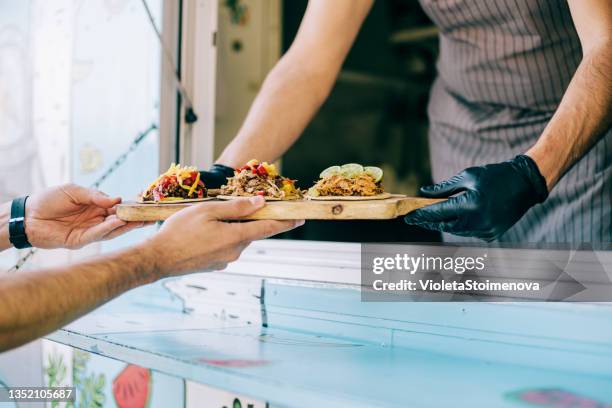 food truck owner serving tacos to male customer. - food truck street stock pictures, royalty-free photos & images