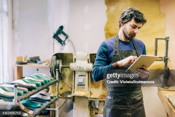 young shoemaker using digital tablet in his workshop. - leather industry stock pictures, royalty-free photos & images
