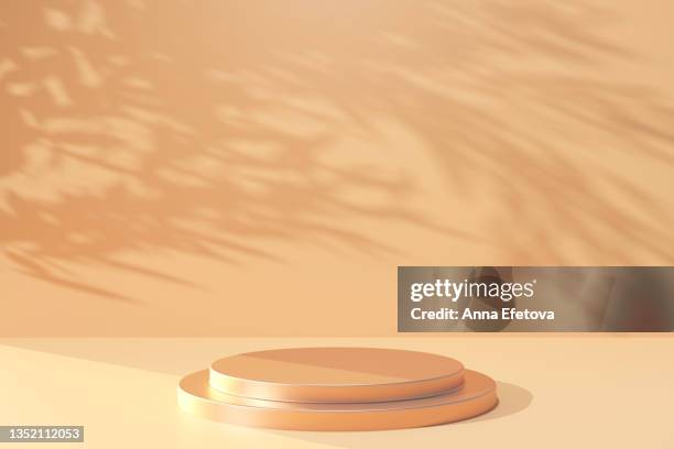 two-tier round gold metal podium on pastel beige background with many plants shadows. perfect platform for showing your products. three dimensional illustration - beige background - fotografias e filmes do acervo