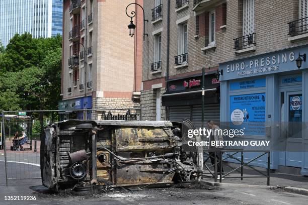 Pedestrian looks at an overturned burnt car in the street in Puteaux, west of Paris on June 30 following riots three days after a 17-year-old boy was...