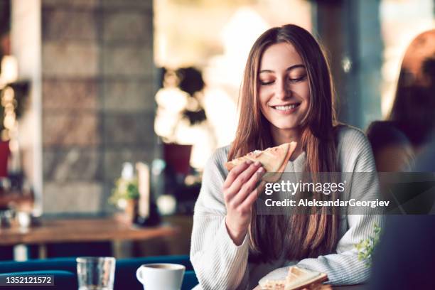 adorabile femmina sorridente prima di prendere morso di toast sandwich con caffè del mattino - una ragazza adolescente foto e immagini stock