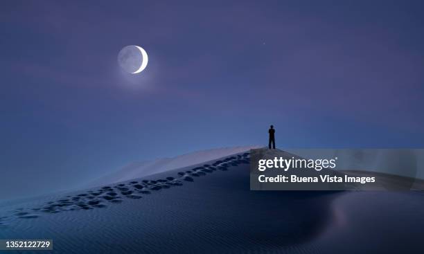 man in a desert watching the moon - desert sky stock pictures, royalty-free photos & images