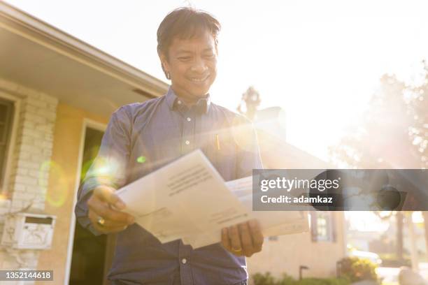 mature filipino person checking the mail at home - junk mail stock pictures, royalty-free photos & images