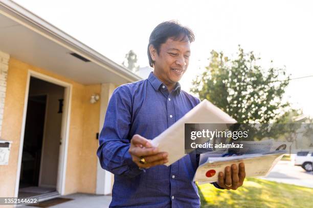 mature filipino person checking the mail at home - junk mail stock pictures, royalty-free photos & images