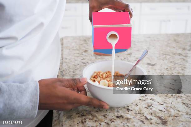 woman pours milk into bowl of cereal - 牛乳パック ストックフォトと画像