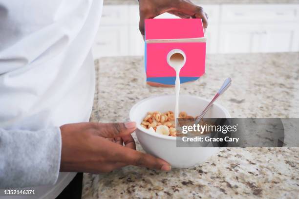 woman pours milk into bowl of cereal - fruit carton stock pictures, royalty-free photos & images