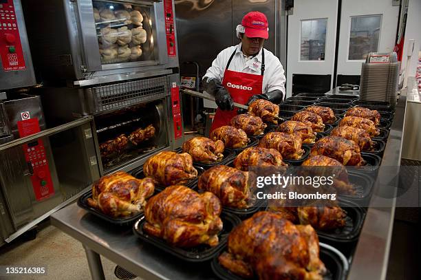 Dios Ruiz, a service deli worker for Costco Wholesale Corp., places cooked rotisserie chickens in containers at a store in San Francisco, California,...