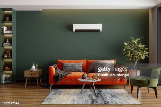modernes wohnzimmer mit klimaanlage, orangefarbenem sofa und grünem sessel - sova stock-fotos und bilder