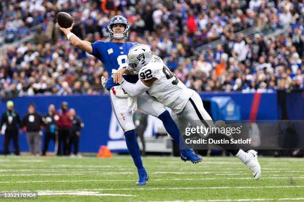 Daniel Jones of the New York Giants throws the ball away while being pressured by Solomon Thomas of the Las Vegas Raiders during the fourth quarter...