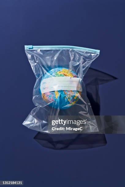 earth globe packed in plastic bag - treibhauseffekt stock-fotos und bilder