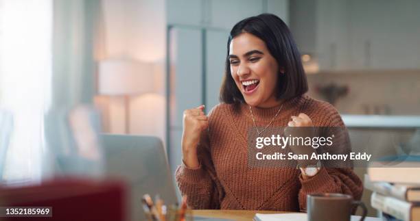 shot of a young woman cheering while using a laptop to study at home - façanha imagens e fotografias de stock